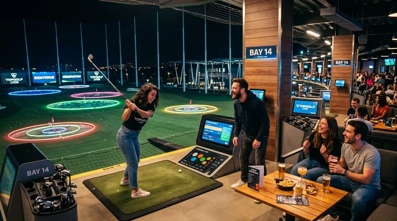 Vue d'une baie de jeu Topgolf moderne et animée en soirée avec des cibles lumineuses en arrière-plan