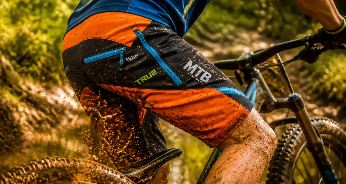 short vtt technique orange noir vététiste sentier